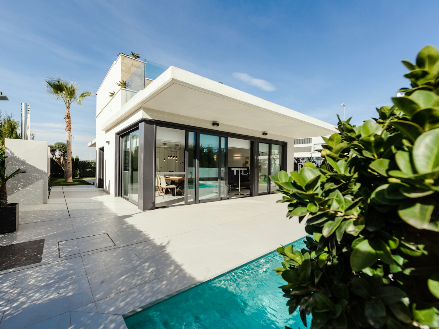 White villa with a private turquoise pool framed by palms
